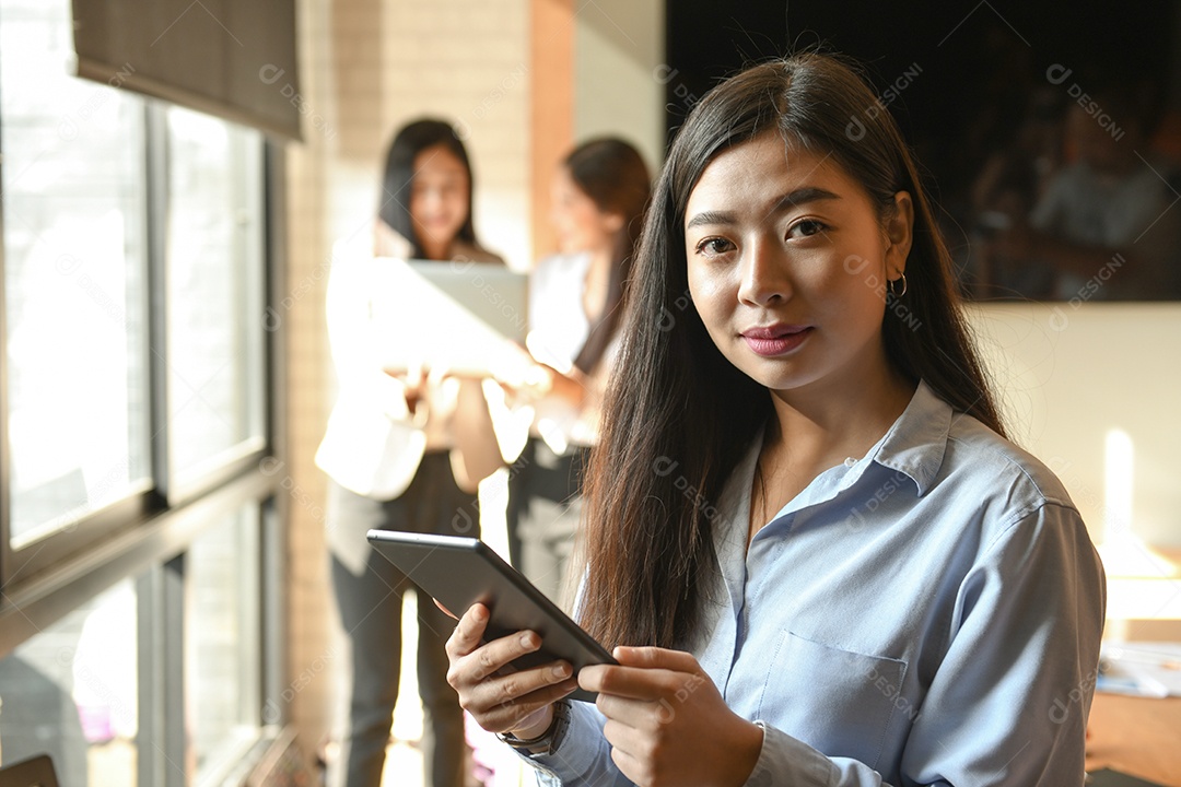Empresária de pé segurando um tablet na mão. A parte de trás do pessoal é um consultor.