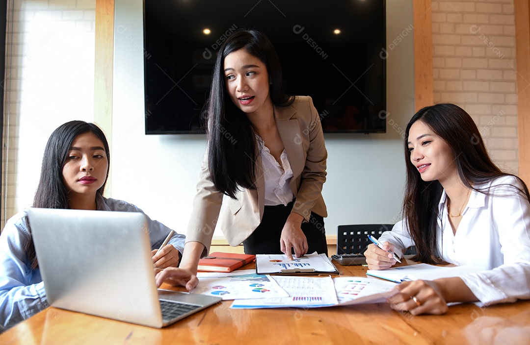 Três jovens estão discutindo o trabalho na sala de conferências, laptop e documento na mesa.