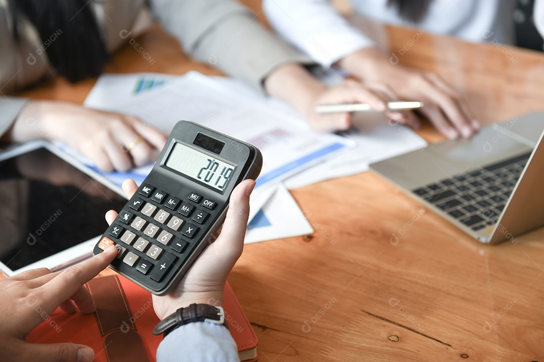 Trabalhadoras de escritório femininas estão usando uma calculadora Número 2019 na tela da calculadora e documento na mesa