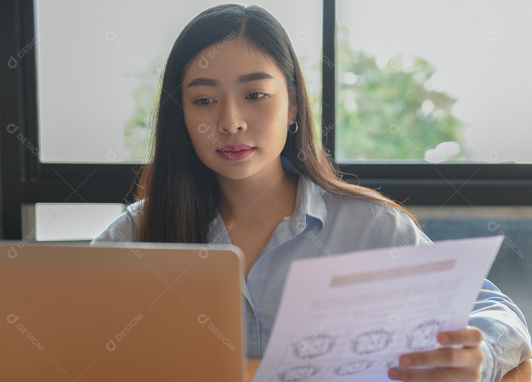 Trabalhadores de escritório feminino usando laptops. Ela tem gráfico na mão.