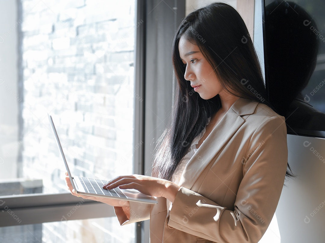 Executivos do sexo feminino estão usando laptop. Ela fica na janela.