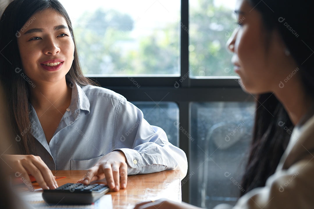 Mulher está usando uma calculadora e conversando com um amigo.
