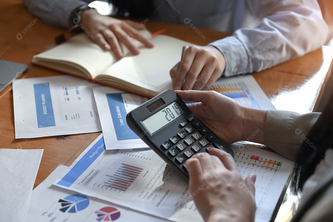 Trabalhadoras de escritório femininas estão usando uma calculadora Número 2019 na tela da calculadora e documento na mesa