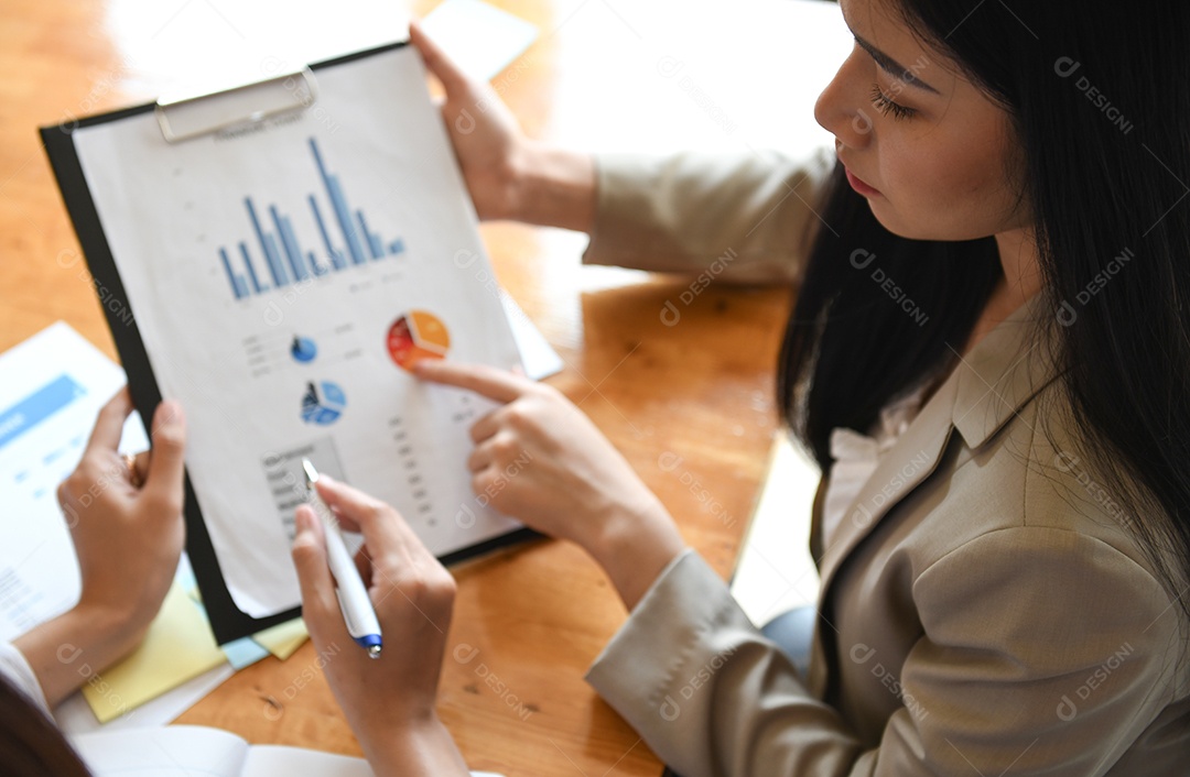 Trabalhador de escritório feminino segurando a folha de dados de gráficos. Eles apontam para gráficos para análise de dados.