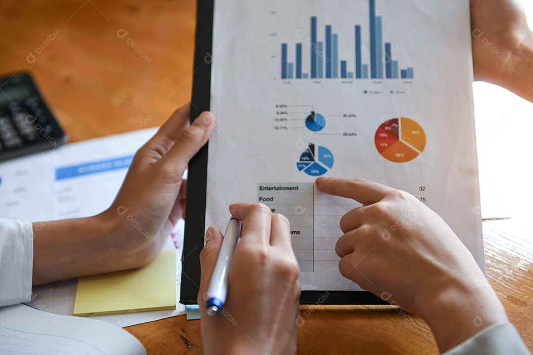 Trabalhador de escritório feminino segurando a folha de dados de gráficos. Eles apontam para gráficos para análise de dados.