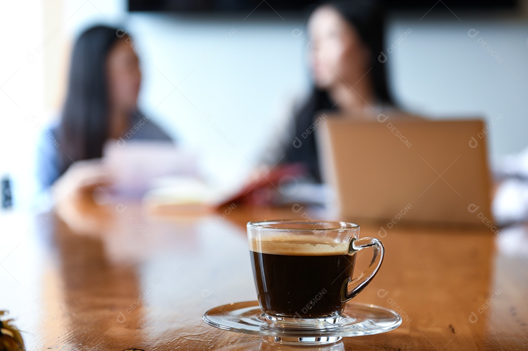 Xícara de café na mesa na sala de reuniões. Trabalhadores de fundo desfocado estão sentados.