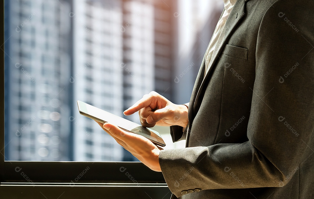 Homem de negócios vestindo terno está usando tablet, homem fica na janela, para conceitos de negócios.