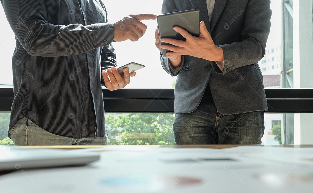 Dois trabalhadores de escritório estão analisando dados. Ambos usam seu smartphone e tablet pela janela. Conceitos de negócios.