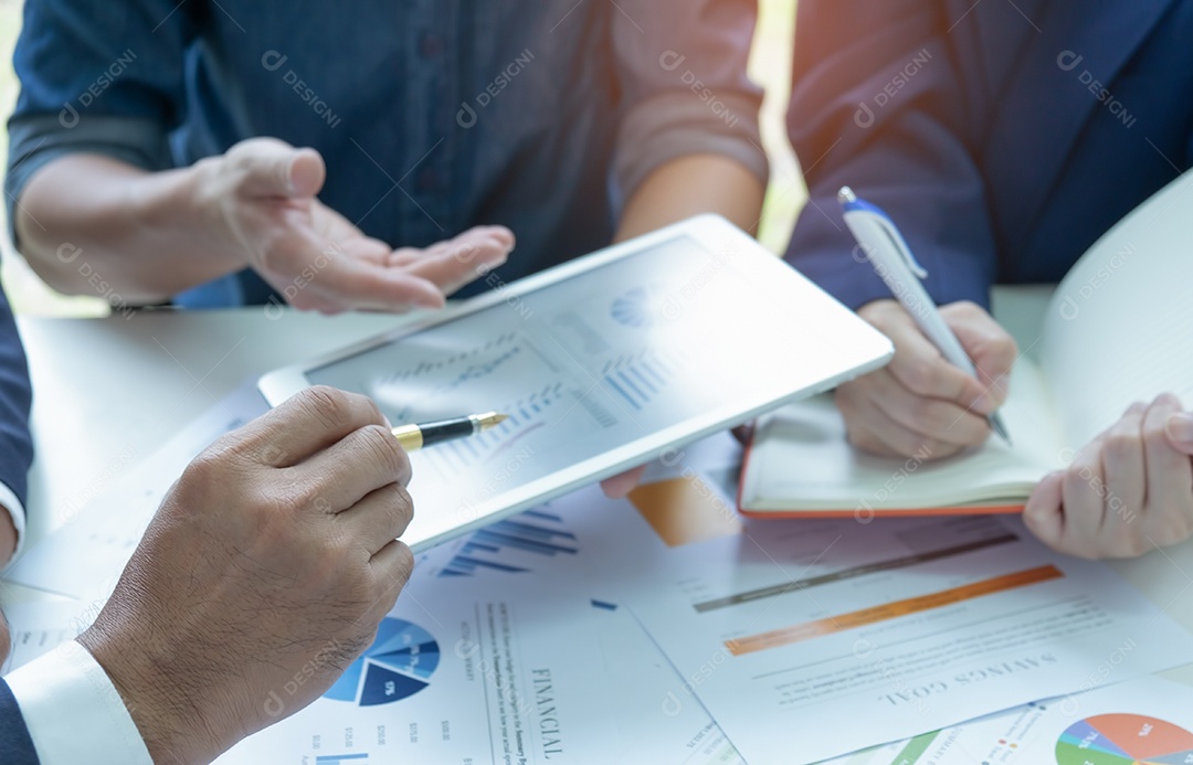 Equipe de negócios está analisando gráficos. Eles usam um tablet e a secretária faz anotações.