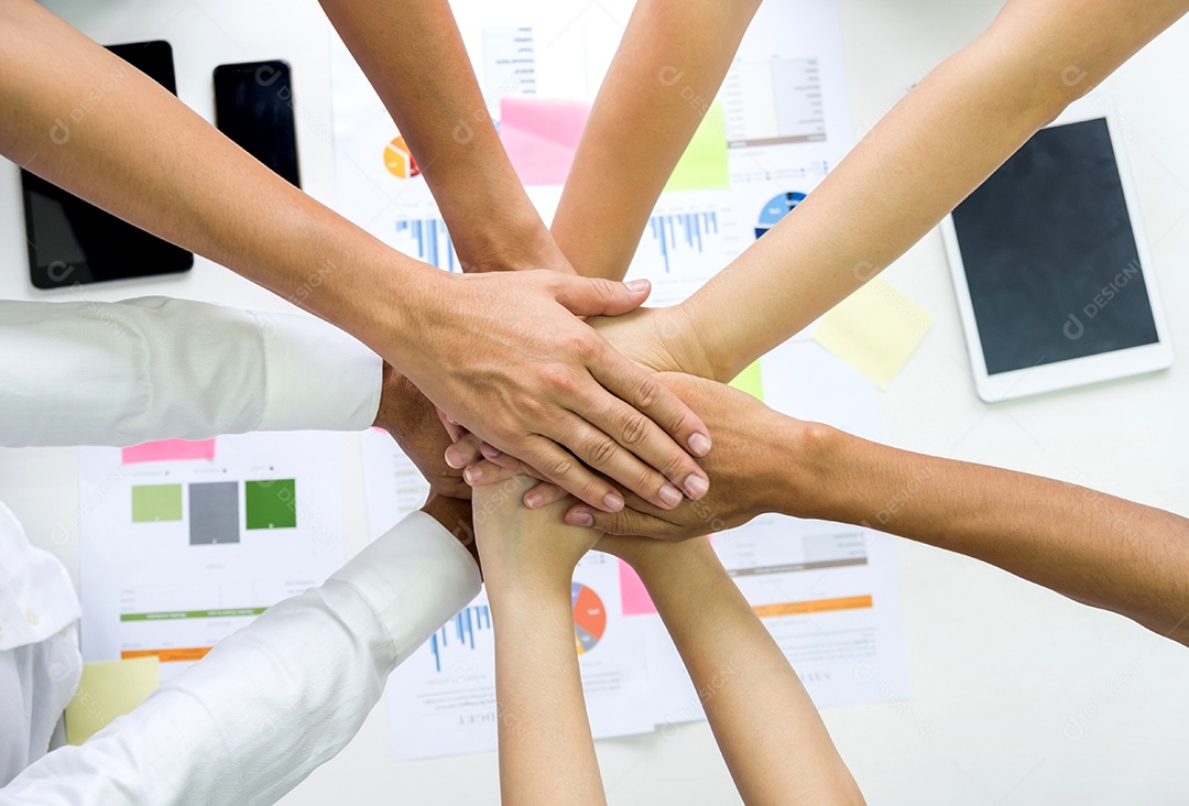 Equipe da equipe aperta as mãos juntas, a equipe de analistas junta as mãos, abaixo de um gráfico colocado na mesa.