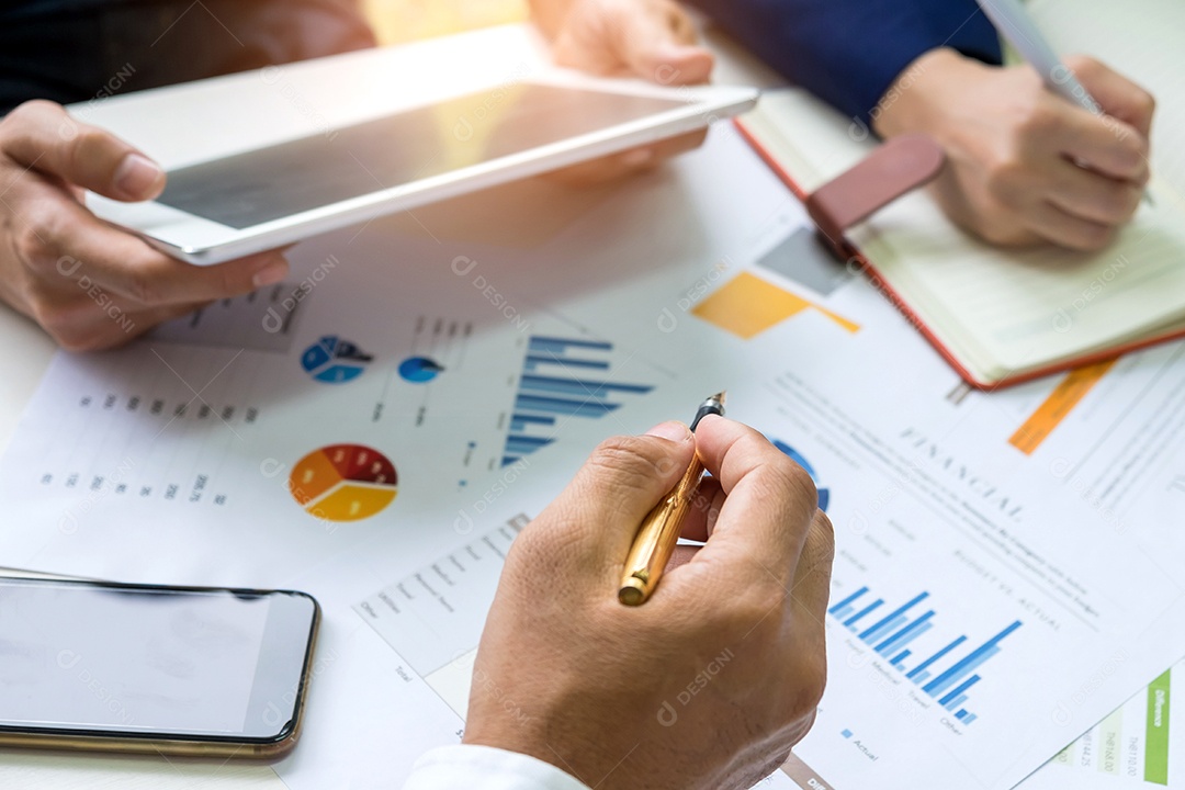 Conceitos de negócios, empresário usa uma caneta apontando para gráfico, trabalhador de escritório usando um tablet e secretária está tomando notas, telefones inteligentes e gráficos na mesa.