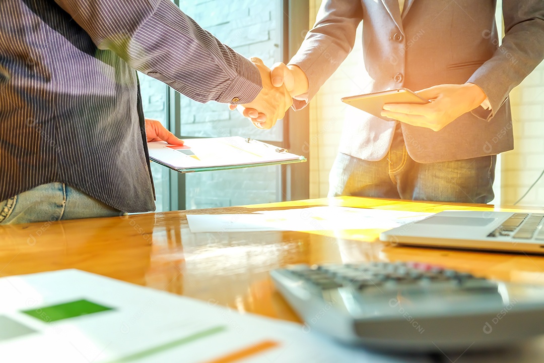 Empresários apertam as mãos ao entrar em negócios, na mão estão arquivos de documentos e smartphones.