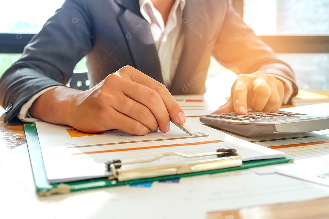Empresário estão usando uma calculadora e uma caneta para analisar dados do gráfico na mesa.