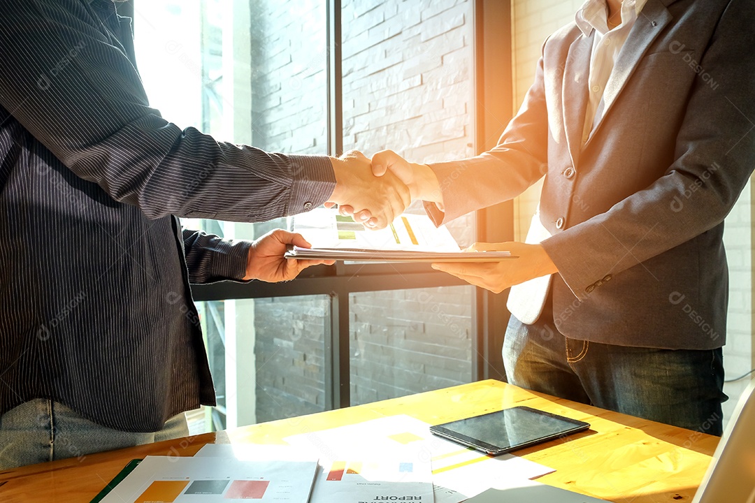 Empresários apertam as mãos ao entrar em negócios, na mão estão arquivos de documentos.