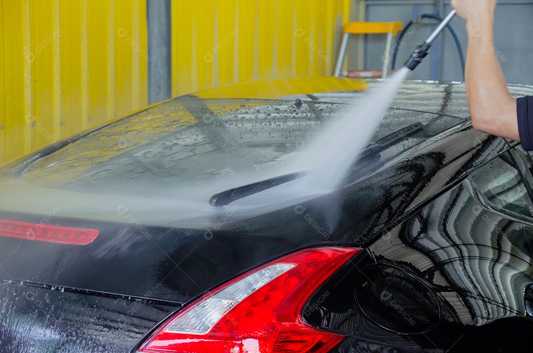 Limpando o carro usando um limpador de alta pressão.