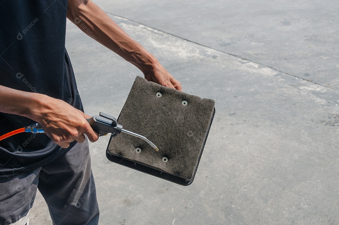 Os homens estão usando o soprador para limpar o carro do filtro de ar.