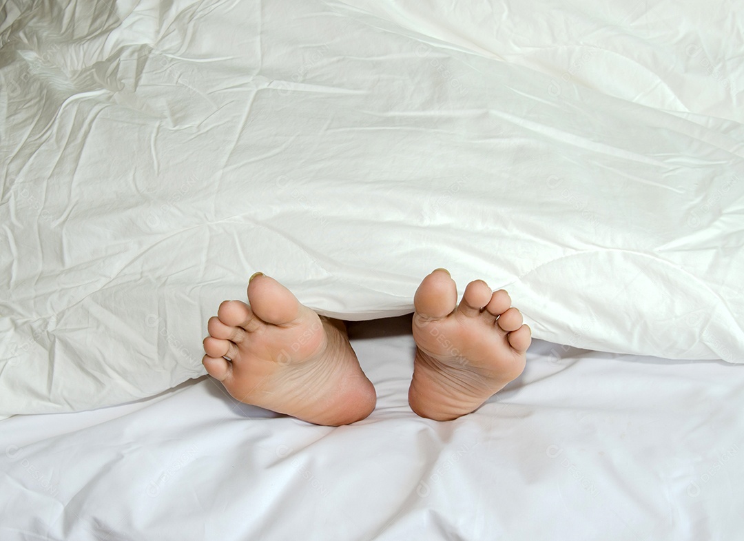 O pé repousa sobre uma cama coberta com um pano branco.