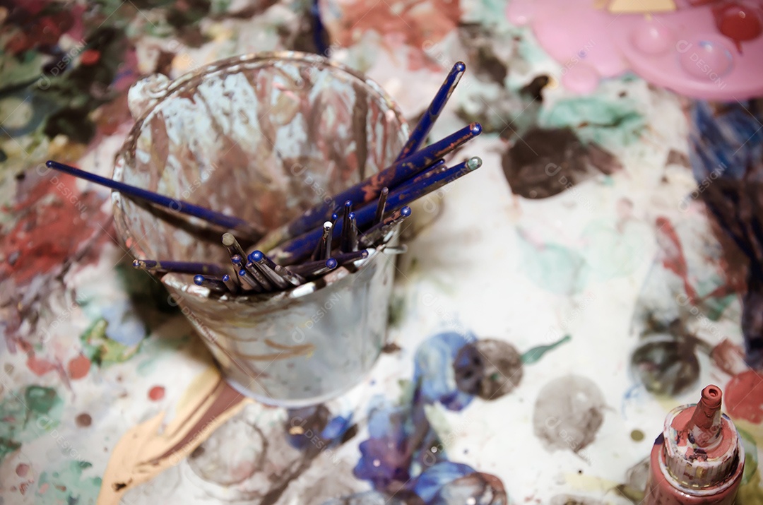 Garrafa de aquarelas colocada na mesa manchada.