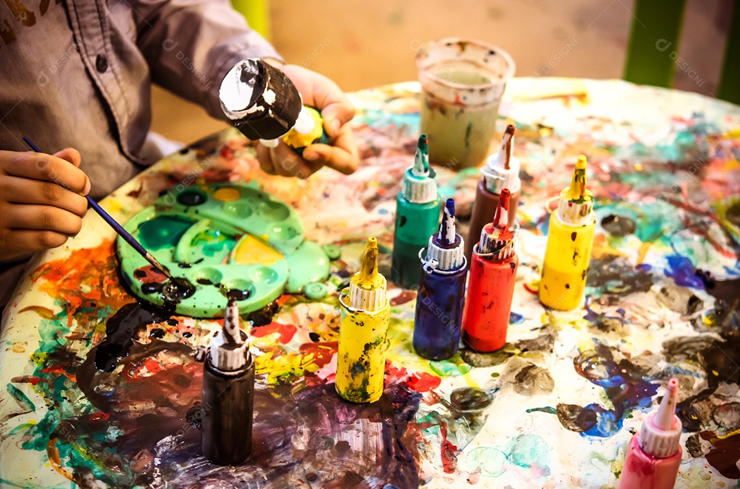 Garrafa de aquarelas colocada na mesa manchada.