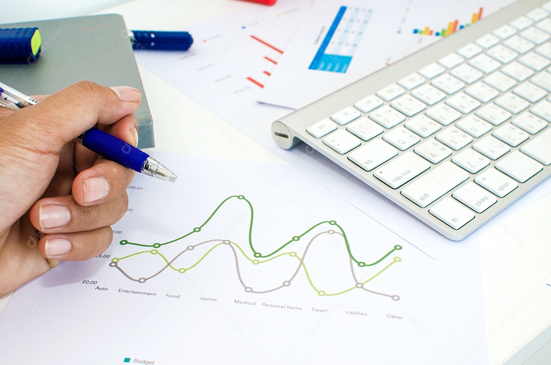 Empresário analisando gráficos de investimento com teclado.