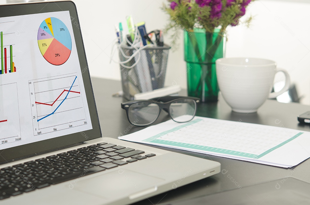 Computador e gráfico na mesa de madeira .