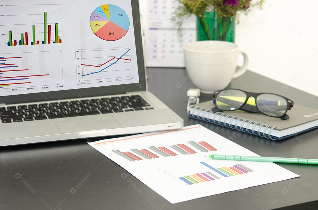 Computador e gráfico na mesa de madeira .