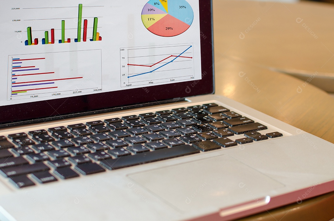 Computador e gráfico na mesa de madeira .