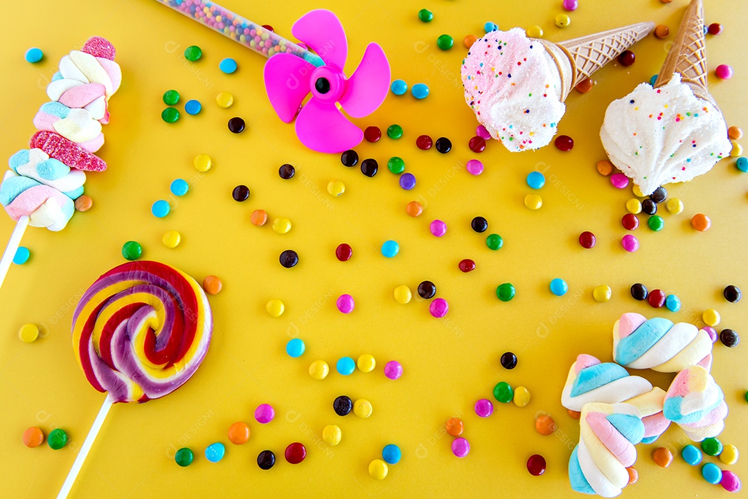 Chocolates, doces e pirulitos em um fundo amarelo