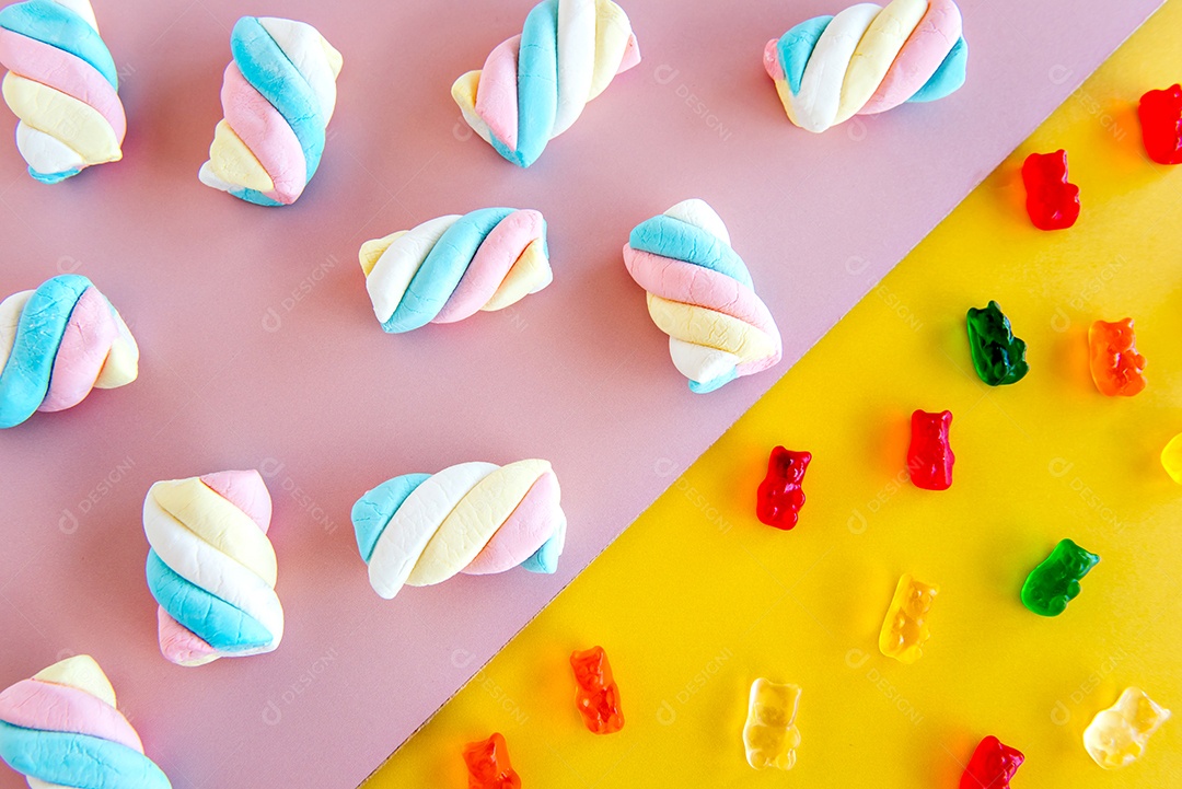Doces coloridos e marshmallows em um background rosa e amarelo