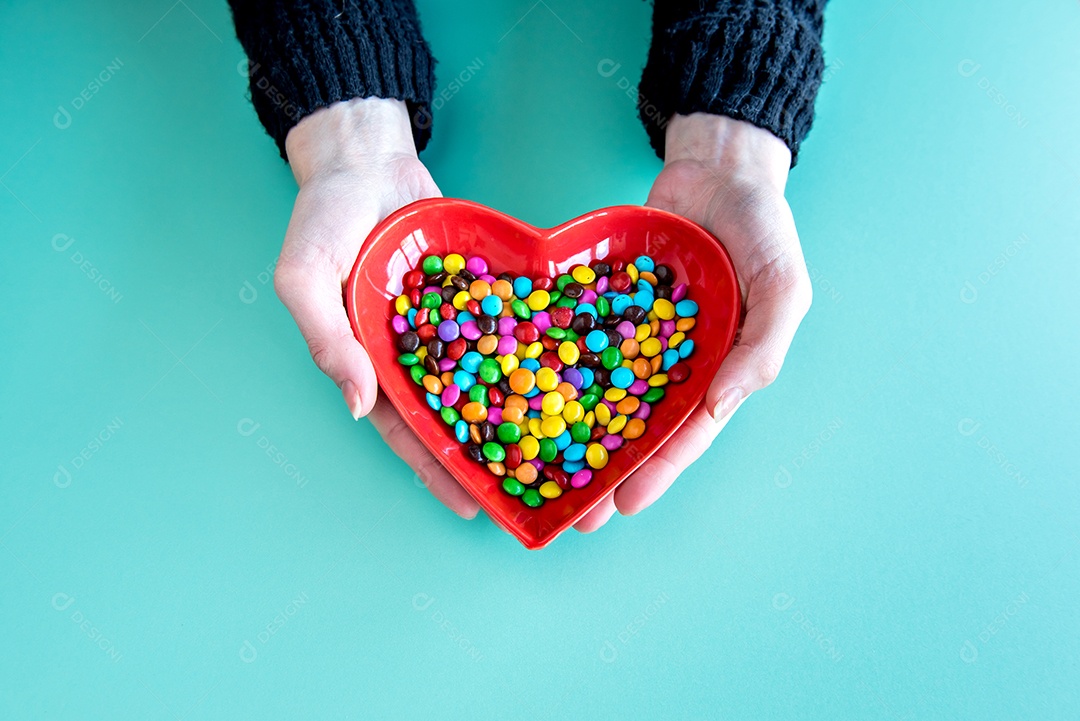 Mãos femininas segurando bombons de chocolate (confetti) no fundo verde