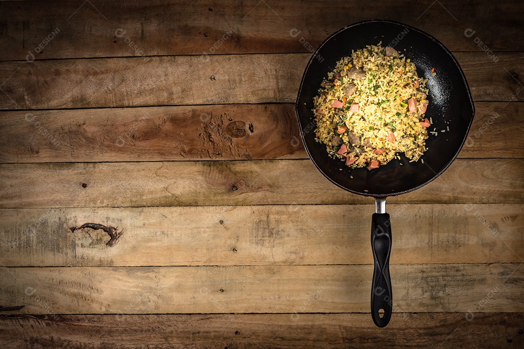 arroz frito com legumes, carne e ovos fritos servido em um prato com pauzinhos