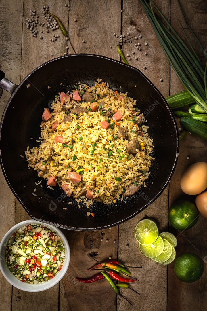 arroz frito com legumes, carne e ovos fritos servido em um prato com pauzinhos