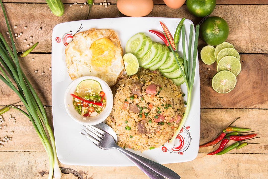 arroz frito com legumes, carne e ovos fritos servido em um prato com pauzinhos