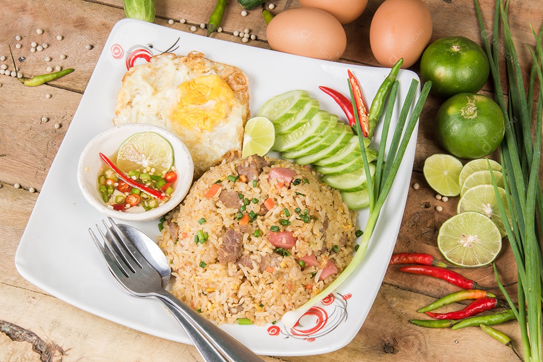 fried rice with vegetables, meat and fried eggs served on a plate with chopsticks
