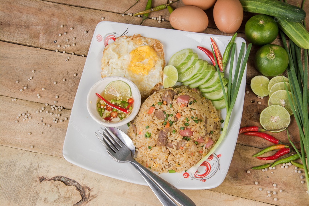 arroz frito com legumes, carne e ovos fritos servido em um prato com pauzinhos
