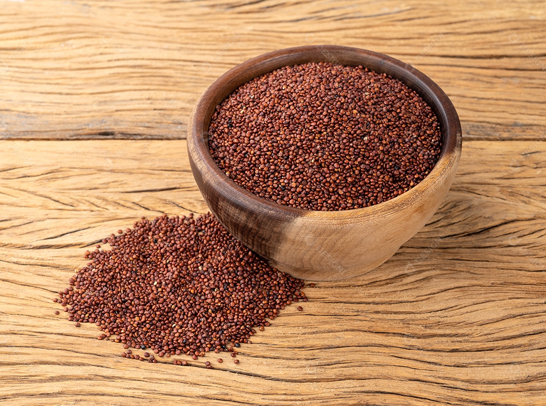 Quinoa vermelha crua em uma tigela sobre a mesa de madeira.