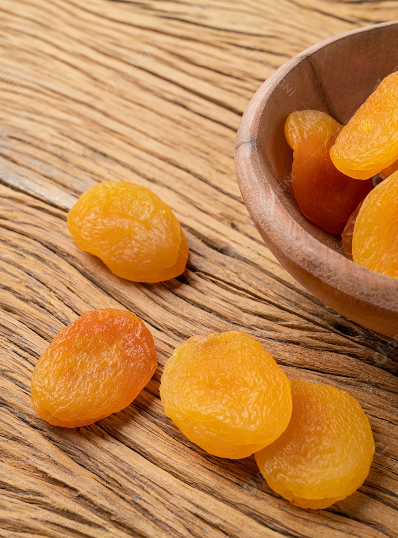 Damascos secos em uma tigela sobre a mesa de madeira.