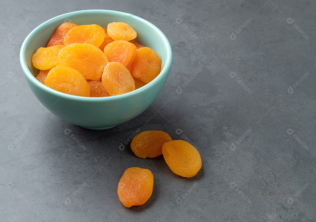 Damascos secos em uma tigela sobre fundo de pedra.