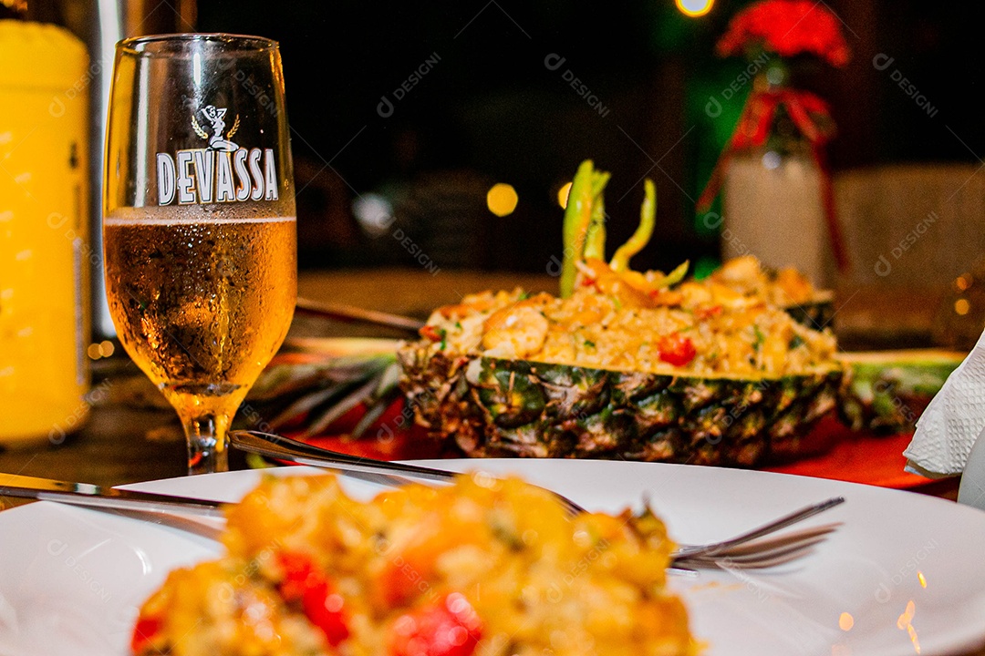 Prato de comida sobre uma mesa de restaurante copo de cerveja Devassa