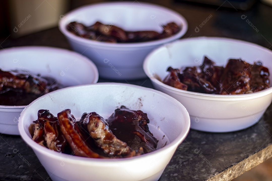 Costeleta com bastante molho servida em marmitas de isopor