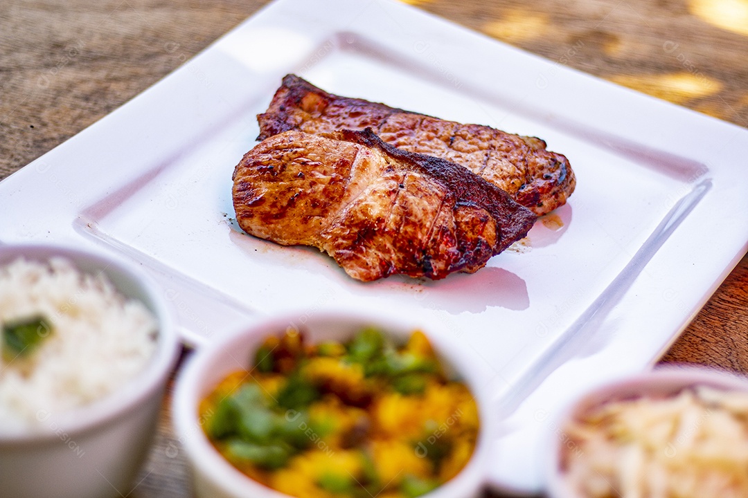 Carne assada suculenta servida em um prato branco com acompanhamentos