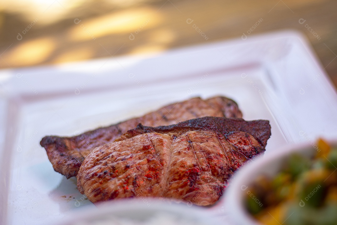 Carne assada suculenta servida em um prato branco com acompanhamentos