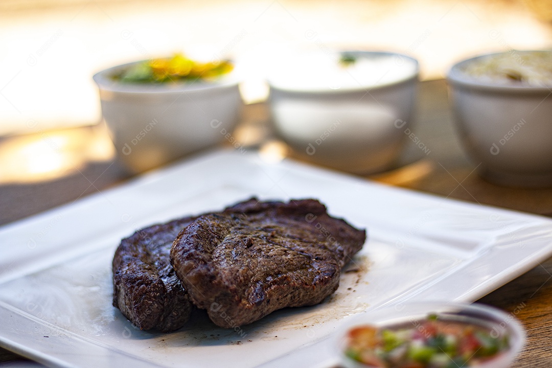 Carne assada suculenta servida em um prato branco com acompanhamentos