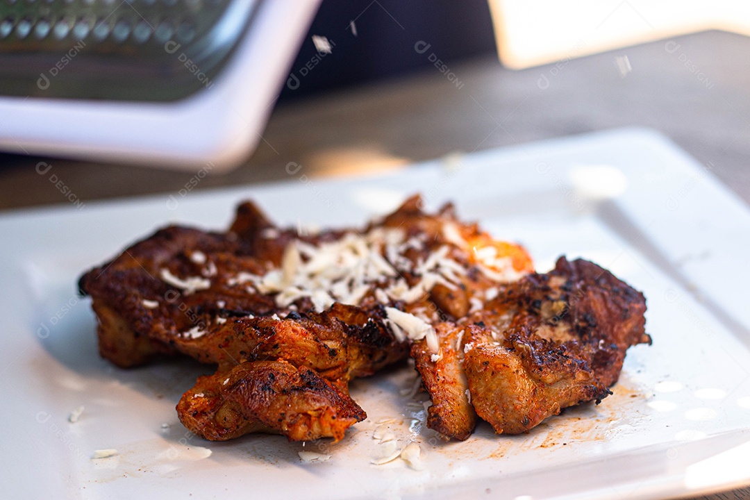 Carne assada suculenta com queijo servida em um prato branco com acompanhamentos