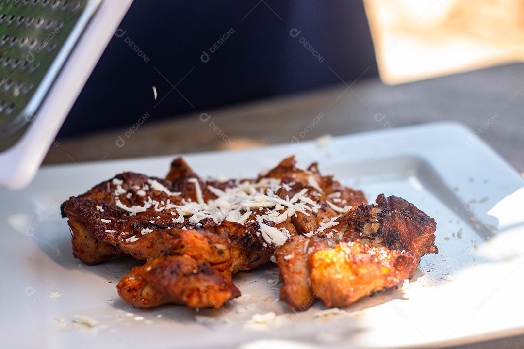 Carne assada com queijo ralado sobre uma prato branco churrasco