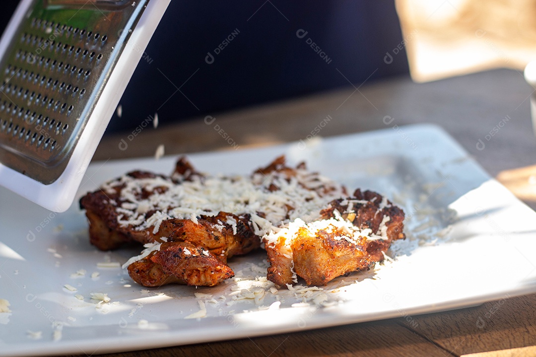 Carne assada com queijo ralado sobre uma prato branco churrasco