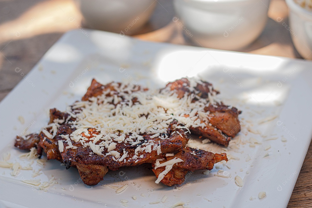Carne assada com queijo ralado sobre uma prato branco churrasco