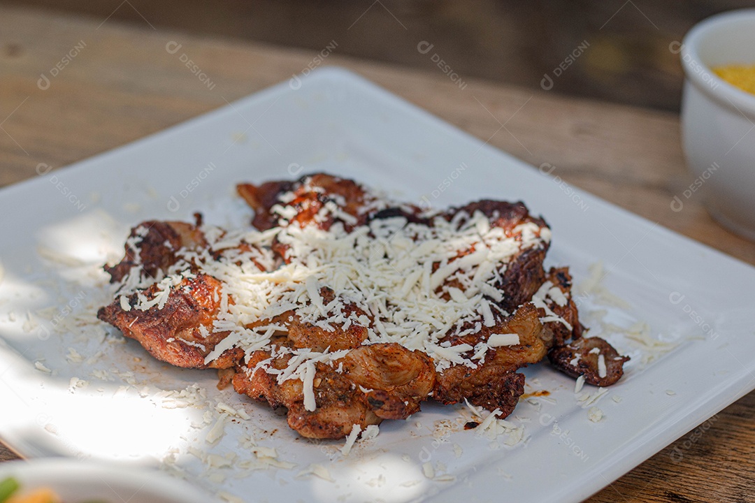 Carne assada suculenta com queijo servida em um prato branco com acompanhamentos