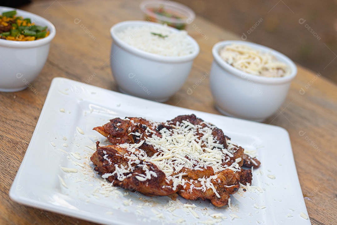 Carne assada suculenta com queijo servida em um prato branco com acompanhamentos