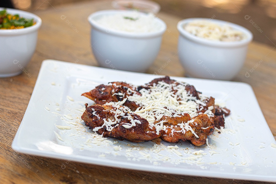 Carne assada suculenta com queijo servida em um prato branco com acompanhamentos